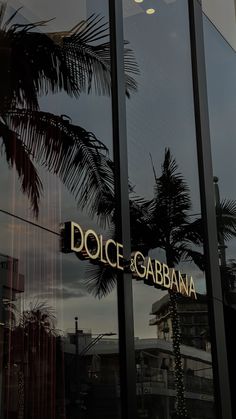 reflection of palm trees in the glass windows of a restaurant called dolce & garbana