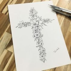 a drawing of a cross with flowers on it and a pen laying next to it