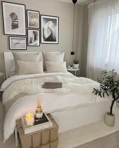 a white bed sitting in a bedroom next to a window with pictures on the wall