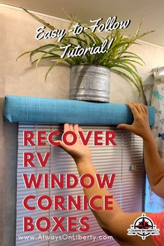 a woman is holding up a blue window curtain in front of a potted plant