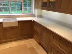 an empty kitchen with wooden cabinets and marble counter tops in front of a large window