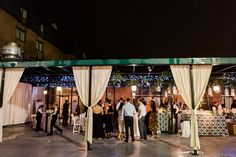 a group of people standing around in front of a white tent with lights on it