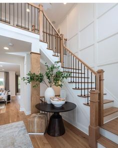 there is a vase with some plants on the table in front of the stair case