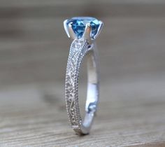 an engagement ring with a blue topazte stone in the center on a wooden surface