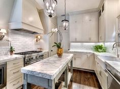 a large kitchen with white cabinets and marble counter tops, along with stainless steel appliances