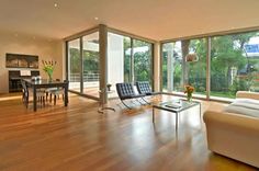 a living room filled with furniture and lots of glass doors that look out onto the backyard