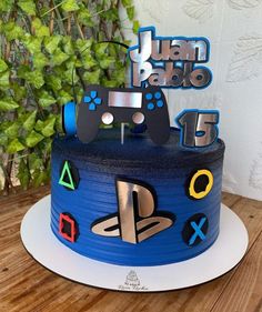 a blue cake with video game controllers and numbers on it, sitting on top of a wooden table