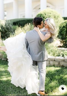 a bride and groom walking through the grass