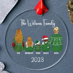 a glass ornament with three people wearing sweaters and hats on it's side