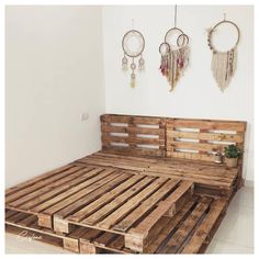 a bed made out of wooden pallets in a room with two hanging dream catchers on the wall