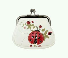 a white purse with a ladybug on the front and red flowers on the back