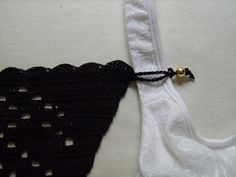 a piece of black crocheted material on white fabric