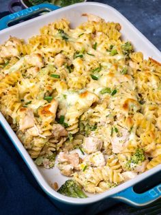 a casserole dish with chicken, broccoli and noodles in it on a blue cloth