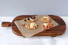 three waffles on a cutting board with fruit and cream sitting on top, ready to be eaten