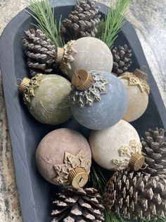 some ornaments are sitting in a tray with pine cones