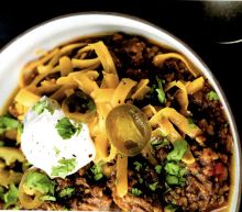 a white bowl filled with taco meat and cheese on top of a black table