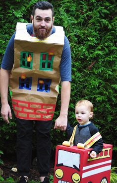 a man in a paper bag costume with a toddler standing next to him and holding a cardboard firetruck