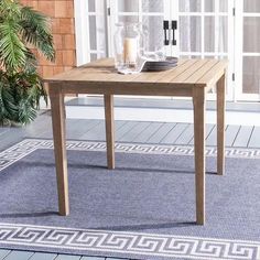 a wooden table sitting on top of a blue rug next to a potted plant