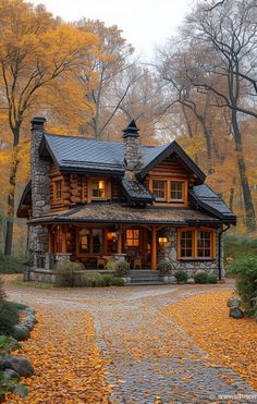 a stone and wood house in the woods with autumn leaves on the ground around it