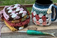 crocheted coffee mug cozys are sitting on a picnic table next to a fishing lure