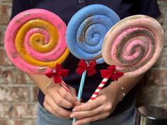 three candy lollipops are being held in front of a brick wall