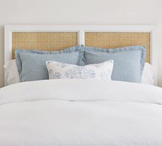 a white bed with blue and white pillows on top of it's headboard