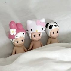 three little figurines with hello kitty hats on their heads and one is wearing a panda hat