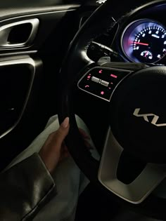 a person is holding the steering wheel while driving in a car with dashboard lights on