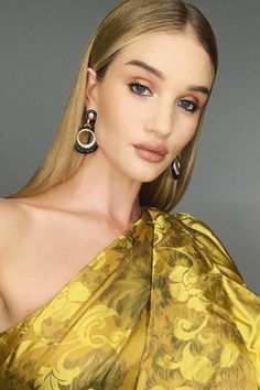 a woman in a yellow dress posing for the camera with large hoop earrings on her head