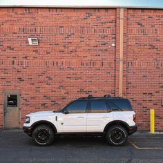 a white suv parked in front of a brick building