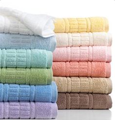 towels stacked on top of each other in front of a white shelf with four different colors