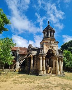 an old church in the middle of a field with blue sky and clouds behind it