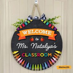 a welcome sign hanging on the front door of a classroom with colorful crayons