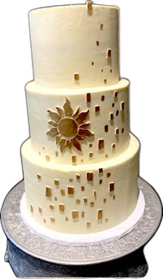 a three tiered cake on a silver platter with an artistic design and gold flowers