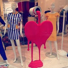 mannequins dressed in colorful clothing with heart - shaped object on display behind them