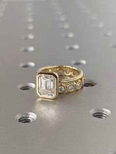 a gold ring with an emerald and diamond set on top of the ring is surrounded by small white dots