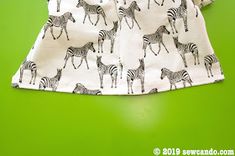 a white shirt with zebras and giraffes on it, sitting against a green background