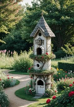 a bird house in the middle of a garden with flowers around it and a pathway