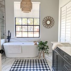 a white bath tub sitting under a window next to a black and white checkered floor