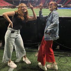 two women standing next to each other in front of a tv screen at a stadium