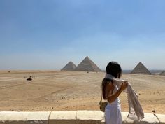 a woman is standing in front of the pyramids