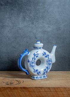 a blue and white teapot sitting on top of a wooden table next to a gray wall