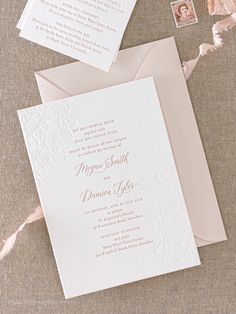 the wedding stationery is laid out on top of each other, including two envelopes and