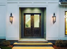 the front door of a house with two lights on it