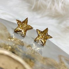 These resin star stud earrings are the perfect addition to your look. Featuring a glittery gold finish, these earrings have 18K gold plated and nickel free posts Gold Starburst Earrings For Party, Gold Starburst Party Earrings, Trendy Gold Earrings With Star Charm, Gold Sparkling Earrings Gift, Sparkling Gold Earrings Gift, Gold Star Earrings For Gift, Gold Star Earrings As Gift, Gold Star-shaped Earrings For Party, Star Shaped Glitter Earrings For Party