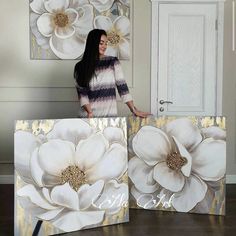 a woman standing in front of two large white flowers on canvases with the word love spelled