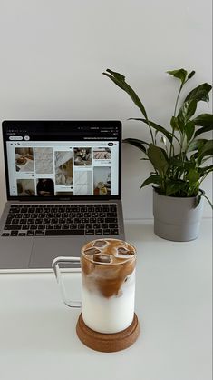 a laptop computer sitting on top of a white desk next to a cup of coffee