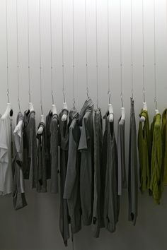 clothes hanging from hooks on a wall next to a white coat rack with several jackets