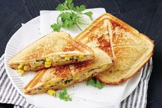 two grilled sandwiches are on a paper plate with garnish and parsley