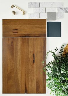 a wooden cabinet sitting next to a potted plant on top of a white wall